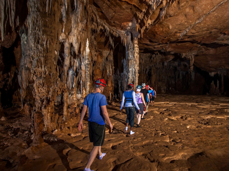 Group of people exploring a cave with stalactites and stalagmites; ATM caves, Actun Tunichil Muknal, Cayo, Belize