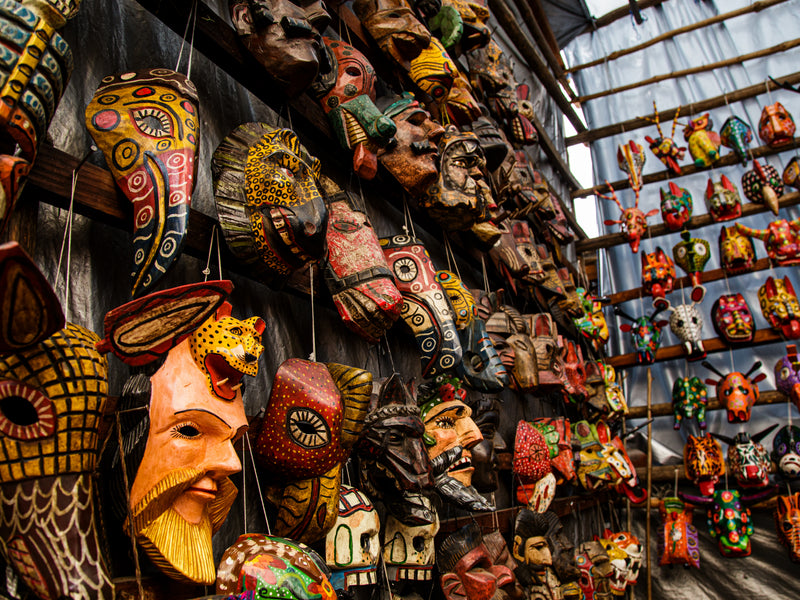 Collection of colorful masks on a wall and shelves; artisan masks, Antigua, Guatemala