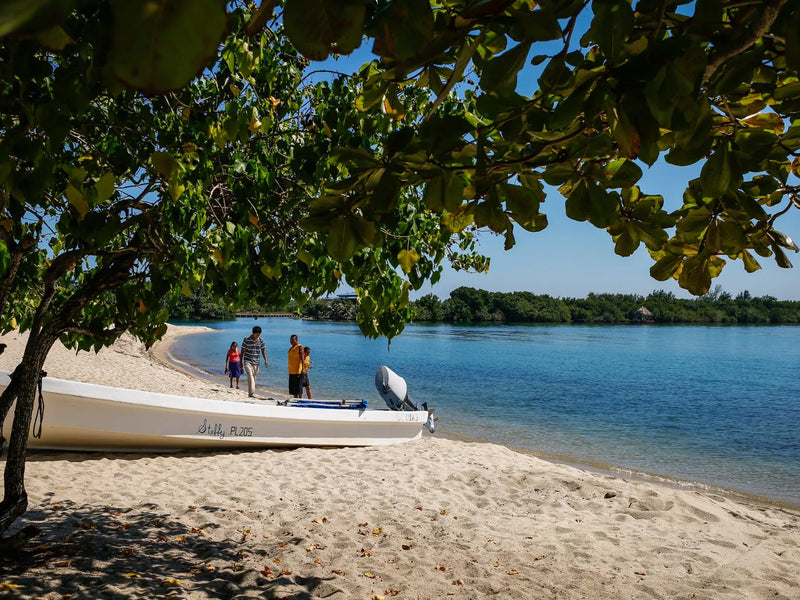 Beach scene with a boat on the sand and people in the distance; Placencia, Belize