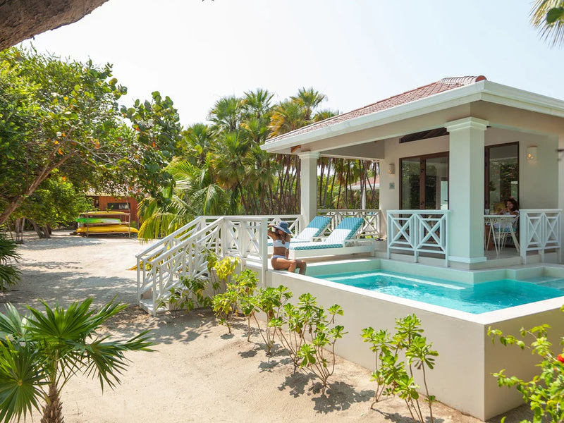 White villa with a pool and lounge chairs surrounded by greenery; Belize Placencia Naia Resort private plunge pool