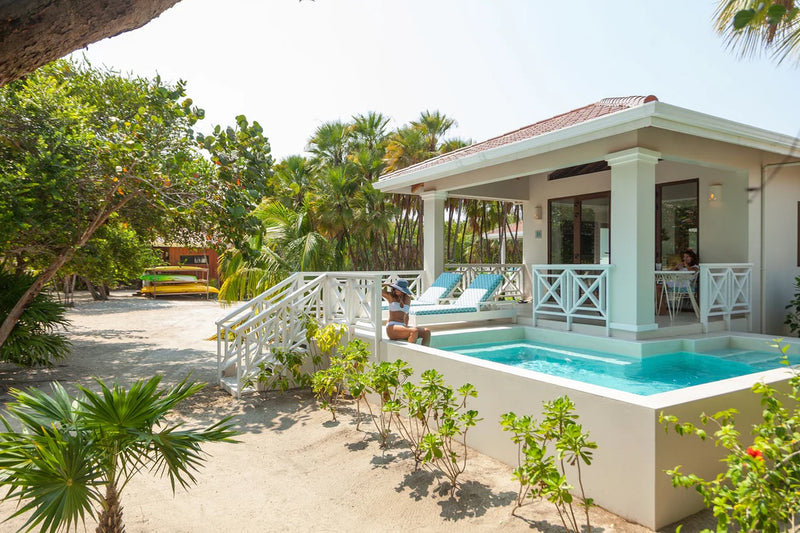 White villa with a pool and lounge chairs surrounded by greenery; Belize Placencia Naia Resort private plunge pool
