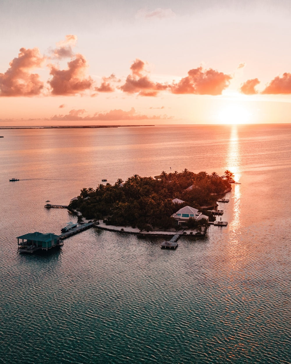 Island with houses and docks at sunset over water; Cayo Espanto Belize