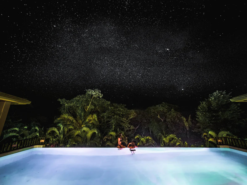 Two people sitting by a pool under a starry night sky, Copal Tree Lodge, Belize