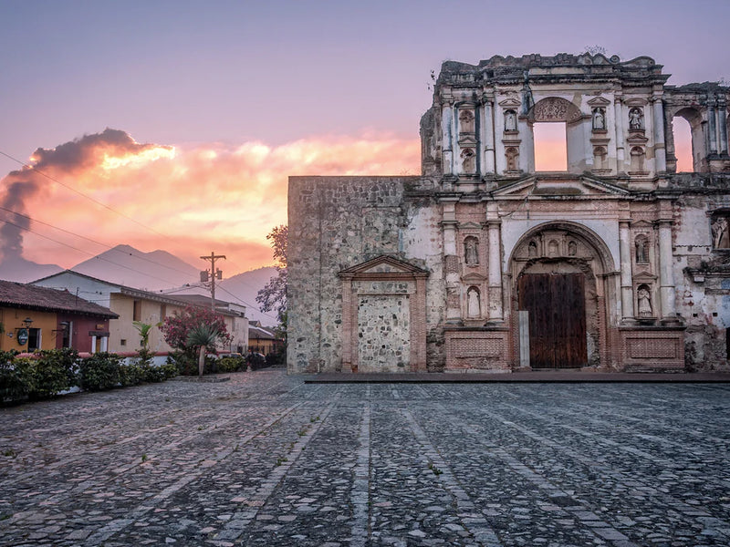 Ruins of a historic building with a dramatic sky and mountain in the background; Antigua, Guatemala
