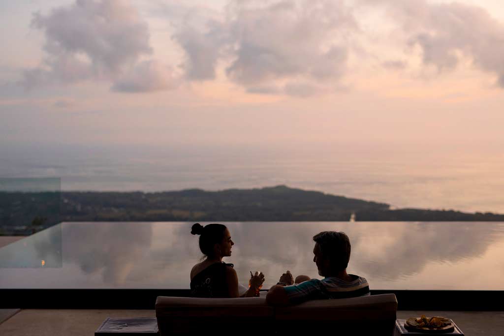 Two people sitting on a couch overlooking a scenic view with a sunset; Kura, Uvita, Costa Rica