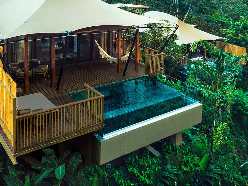 Wooden cabin with a pool and deck surrounded by lush greenery; Arenal Nayara Tented Camp, La Fortuna, Costa Rica