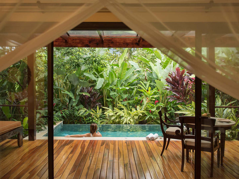 Wooden deck with pool and dining area surrounded by lush greenery, Nayara Springs plunge pool