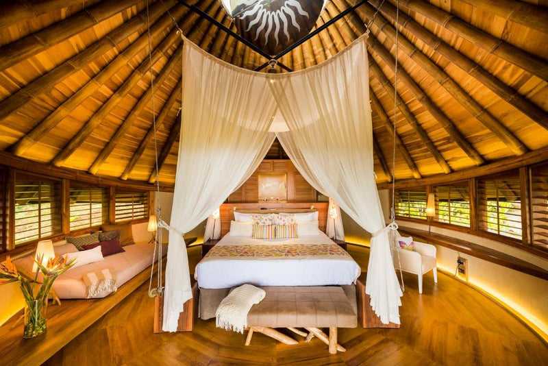 Wooden bedroom with canopy bed and thatched ceiling; Origins Lodge Upala Costa Rica