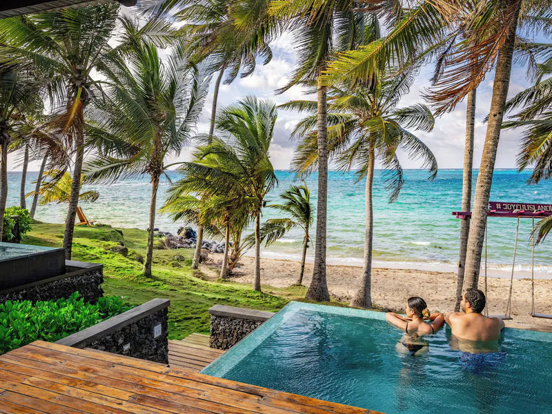 Two people in a pool with a scenic view of the ocean and palm trees. Yemaya, Little Corn Island, Nicaragua.