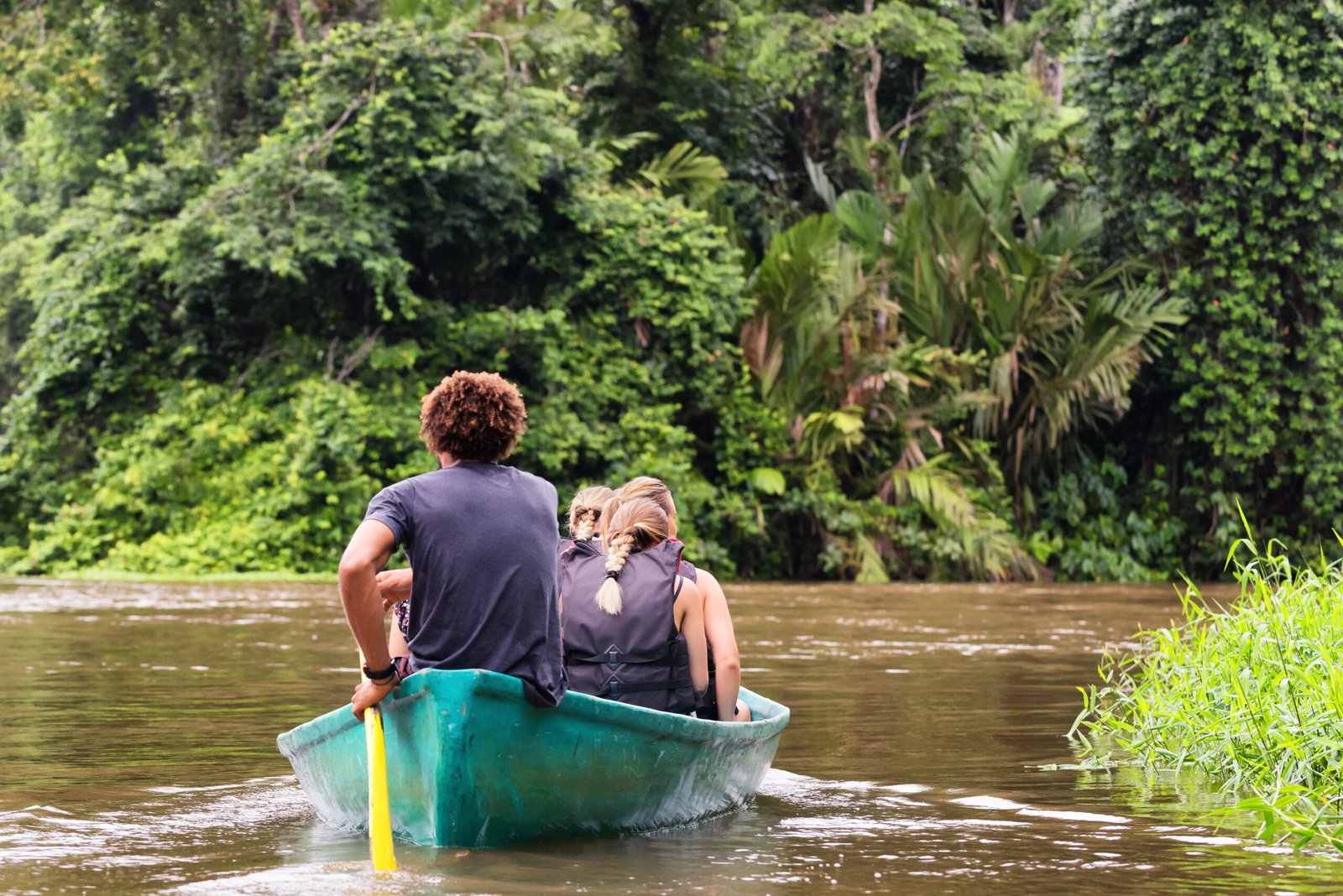 People exploring a wild nature area by rowing boat, ecotourism concept. Tortuguero national park. Costa Rica.